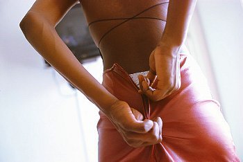 A woman zipping up a pink satin skirt